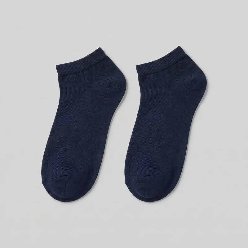 A matching pair of navy ankle socks is shown flat, with the full foot shapes, rounded closed toes, shaped heel pockets, and short ribbed cuffs visible. The socks have a fine vertical knit texture, visible toe seam shaping, and smooth unembellished surfaces without logos, prints, patches, embroidery, or other embellishments.