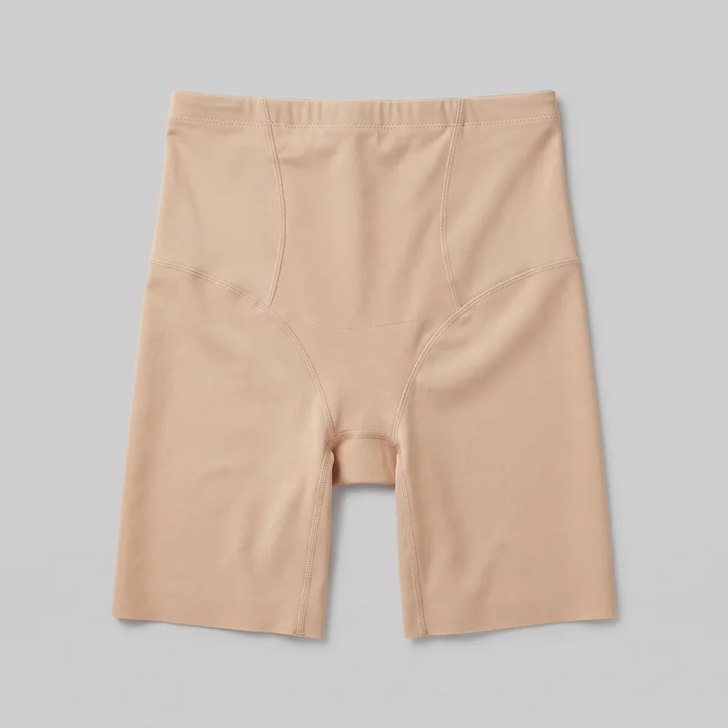 Beige high-waisted shaping shorts shown flat in a standalone front view. The garment has a wide waistband, curved vertical front panel seams, curved hip seam arcs, a visible crotch gusset area, overlock seam finishing, and straight hems ending at mid-thigh.