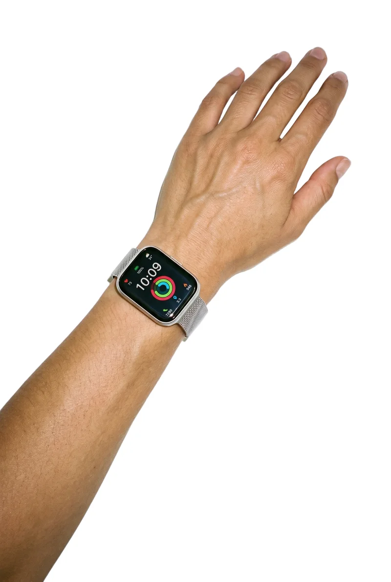 A women's silver smartwatch worn on an angled hand and wrist, shown from a top view. The hand and wrist are framed against a pure white backdrop.
