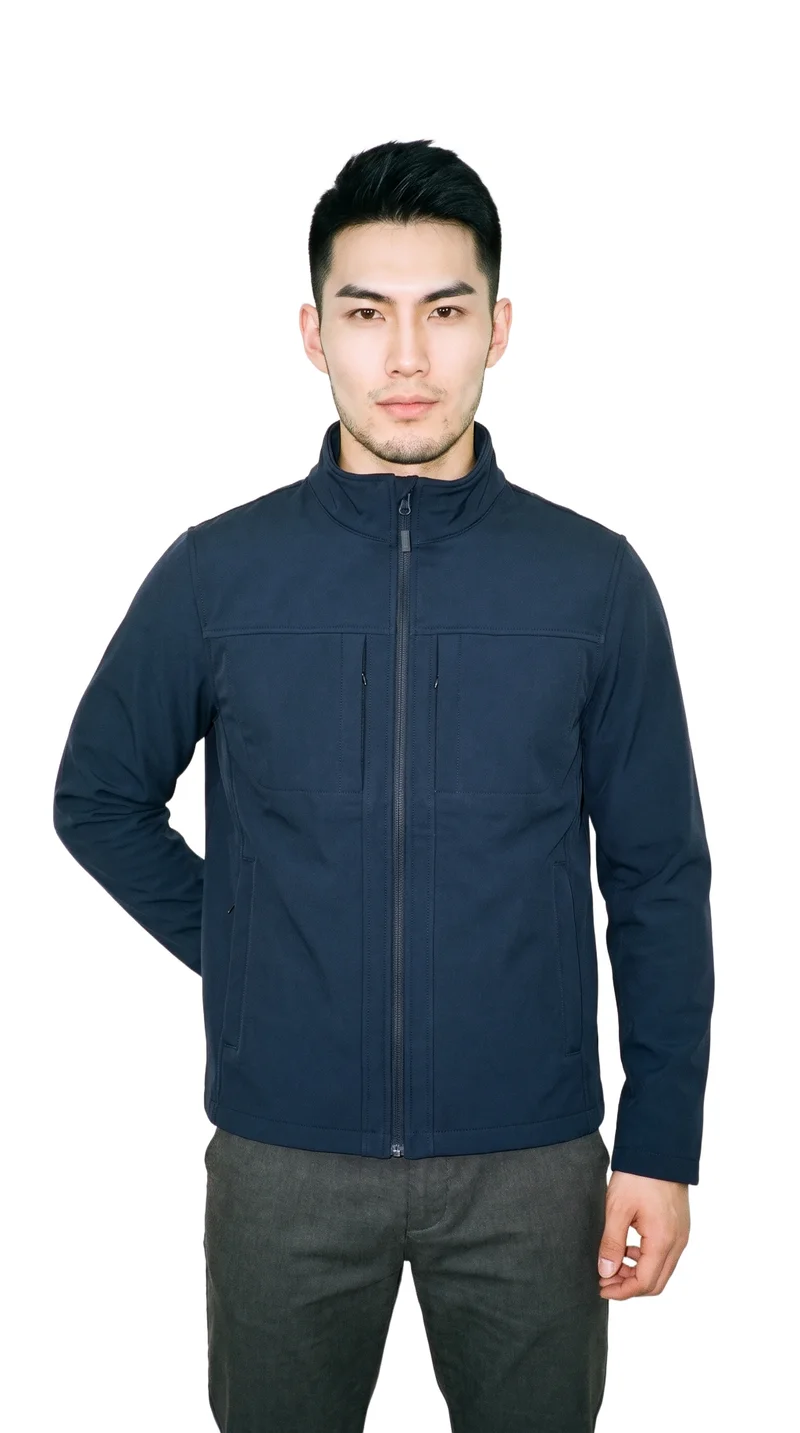 An 18-year-old Chinese man wears a men's navy softshell jacket in a 3/4-length front view, with one hand on his lower back and a natural expression. The jacket is shown against a pure white backdrop.
