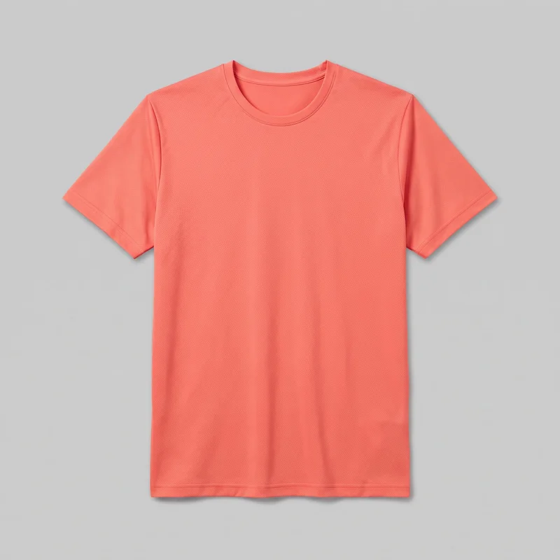 A complete front view of a plain coral short-sleeve crew-neck T-shirt laid flat. It has a regular straight silhouette, set-in shoulders, a rounded ribbed neckband, visible shoulder seams and sleeve hems, a full-length body, and a straight stitched bottom hem. The fabric surface has a fine all-over texture, with no visible logos, prints, patches, embroidery, or embellishments.