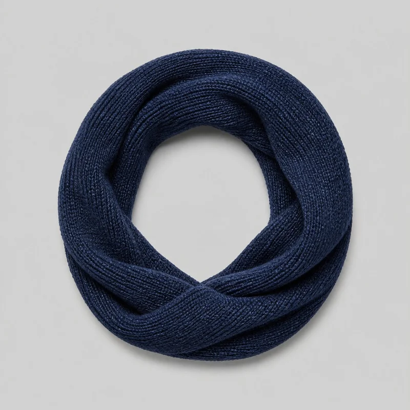 A navy women's snood is shown from above as a complete continuous-loop scarf arranged in overlapping circular layers around a central opening. Its dense ribbed knit texture and thick, folded rounded edges are clearly visible.