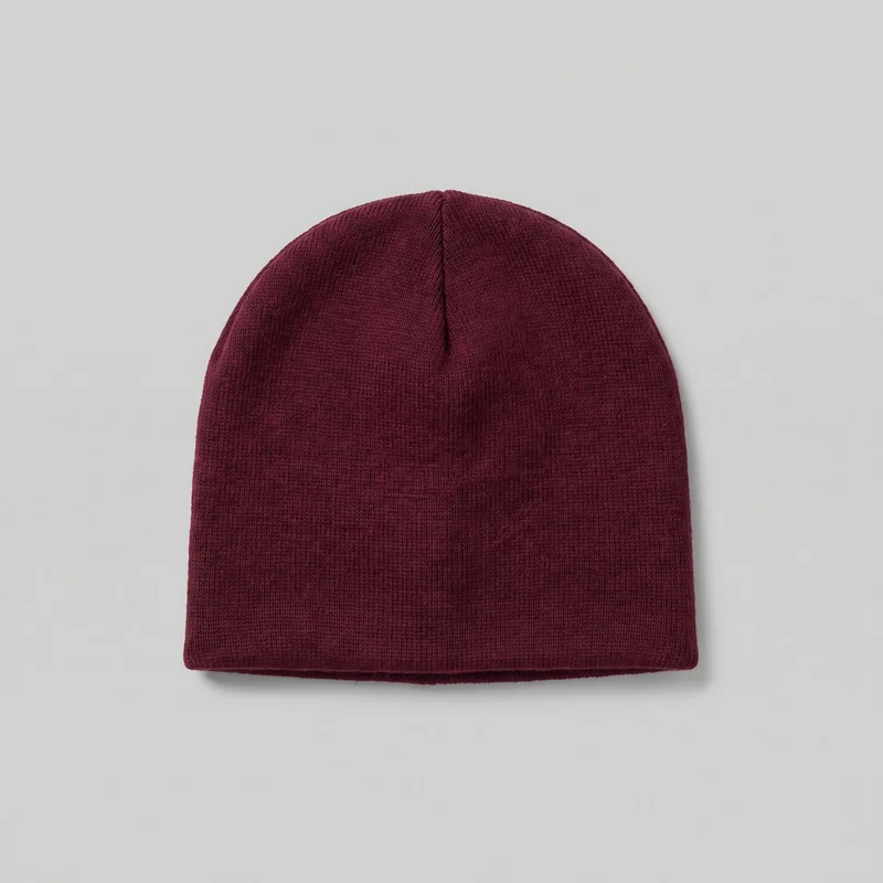 A standalone burgundy beanie with a close-fitting, cuffless pull-on design. The complete hat has a rounded dome crown, a straight lower opening with a narrow finished edge, fine vertical ribbing throughout, and visible seams or darts converging at the top.