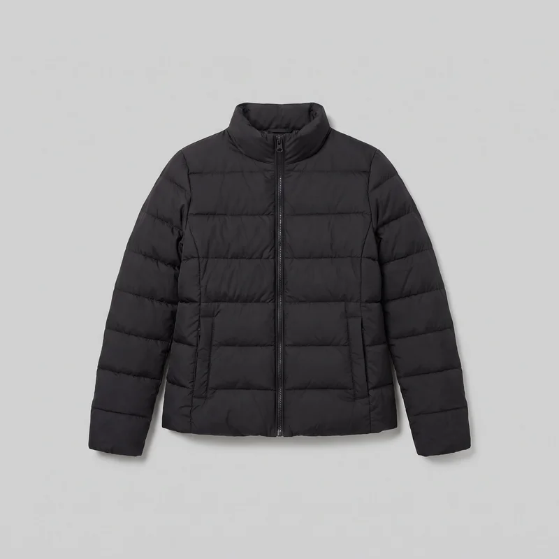 A mostly complete front view of a women's black quilted puffer jacket laid flat against a backdrop. The hip-length jacket has a straight silhouette, high stand collar, full center-front zipper, long sleeves, horizontal padded baffles across the torso and sleeves, vertical front panel seams, and two lower vertical zip pockets set into rectangular panels.