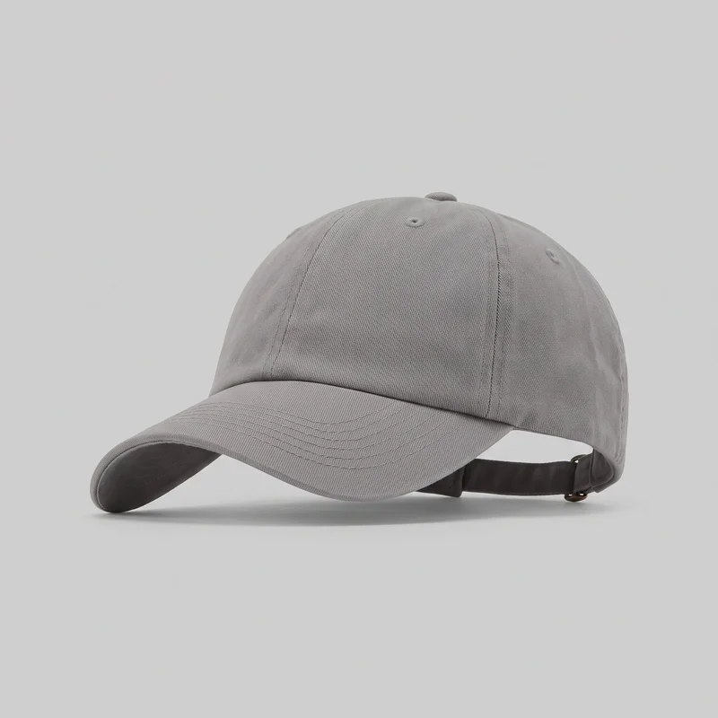 A grey six-panel dad cap is shown mostly complete from a front three-quarter angle. The rounded crown has vertical panel seams, visible ventilation eyelets, and a top button, while the curved brim features multiple parallel rows of stitching and a bound outer edge. A rear cutout with an adjustable strap and metal slide buckle is also visible; no logos, prints, patches, embroidery, or embellishments are shown.