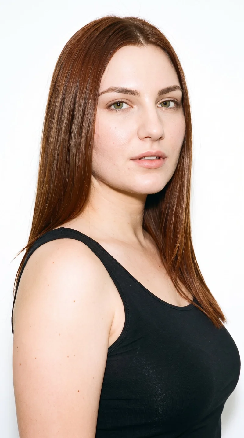 A 23-year-old Slavic woman with fair skin and a peach undertone has an oval face with balanced proportions and a softly rounded jaw. Her medium-thickness eyebrows frame green eyes, and her lips are medium in fullness. Straight chestnut-brown hair with a reddish undertone is parted evenly at the centre and worn smooth.
