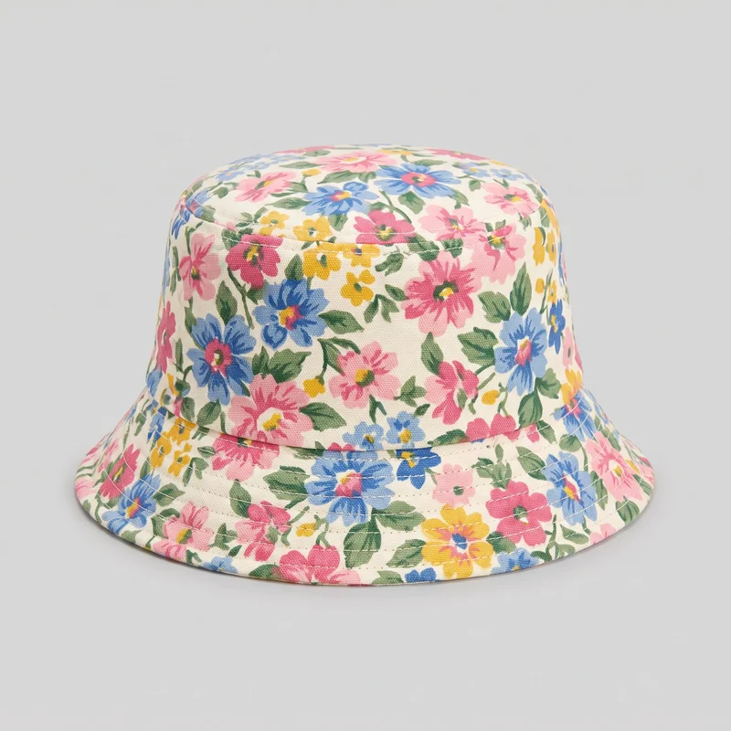 A complete women's floral print bucket hat is shown alone from a slightly elevated front angle. It has a rounded flat crown, cylindrical side band, and downward-sloping brim with a horizontal construction seam and multiple parallel stitch rows. Scattered blossoms, leaves, and stems cover the crown and brim.