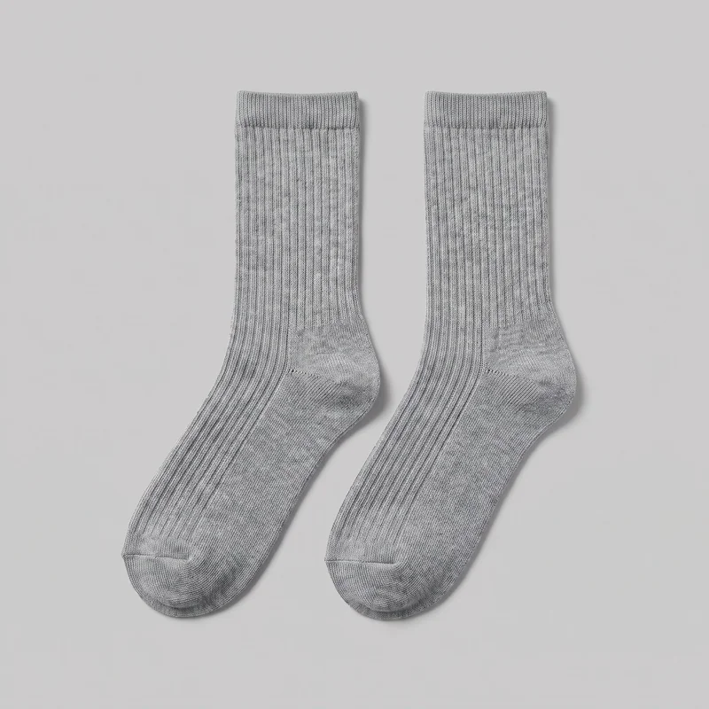 A matching pair of grey ribbed crew-height socks is laid flat, shown mostly complete from the ribbed cuffs to the rounded toes. The view shows the straight ribbed shafts, shaped heel pockets, and continuous vertical rib knit texture across the tops of the feet.