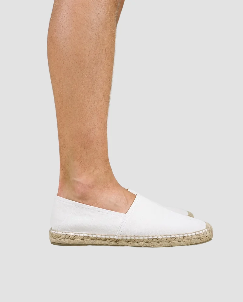 A men's white espadrille shown from the side with the foot flat, framed from the ankle down against a Fog Grey flat-color backdrop.