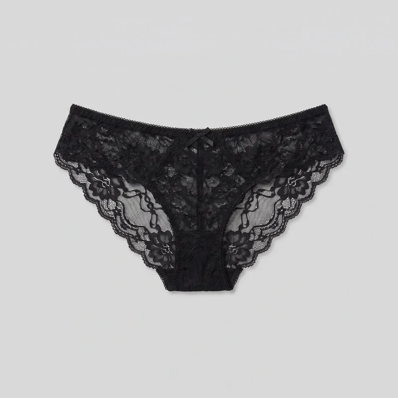 A black women's lace bikini brief is shown laid flat in a complete front view. The low-rise brief has a narrow picot-trim waistband with a small centered bow, sheer floral lace across the body, scalloped edging around the high-cut leg openings, and a full triangular front panel narrowing toward the crotch. Center-front seaming and panel joins are visible.