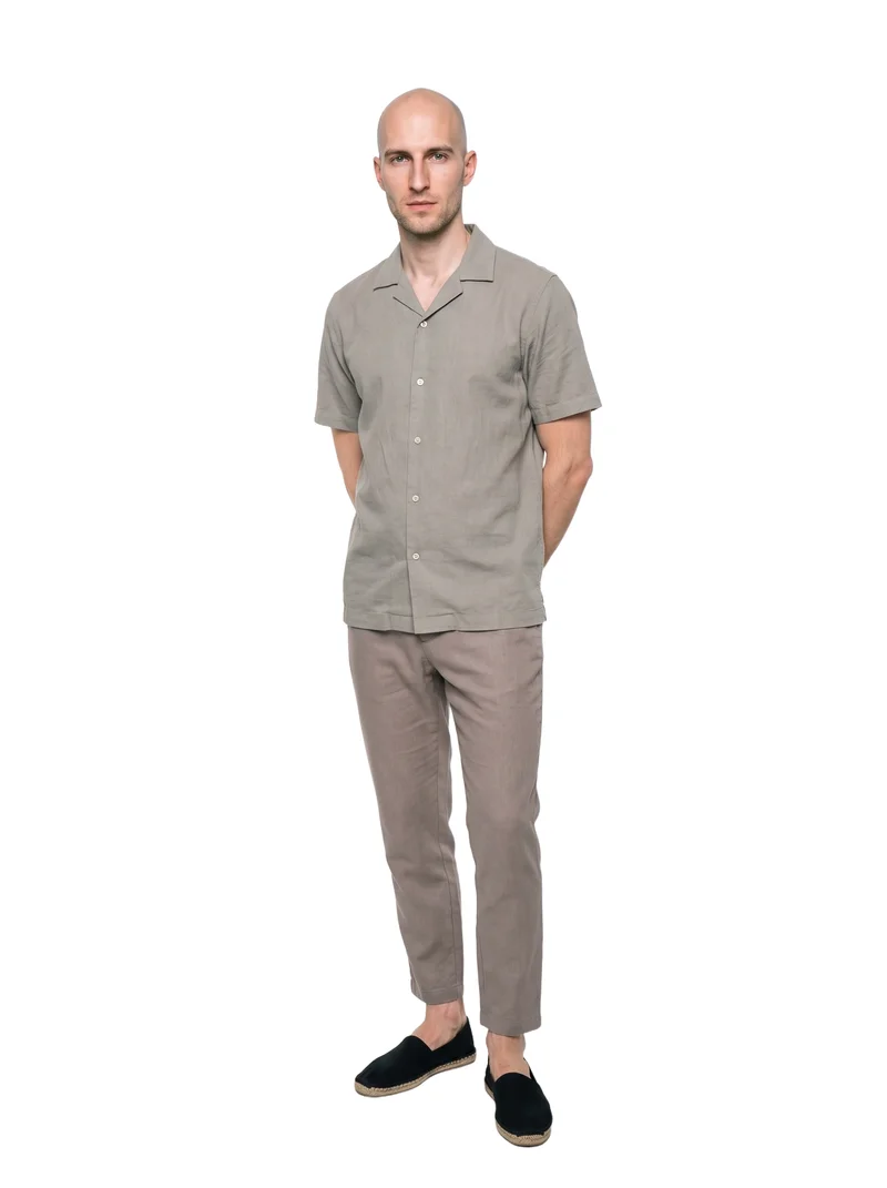 A 31-year-old Caucasian man is shown full body from the front, wearing black espadrilles and standing with his hands behind his back. He has a serious expression, and the image uses a pure white backdrop.
