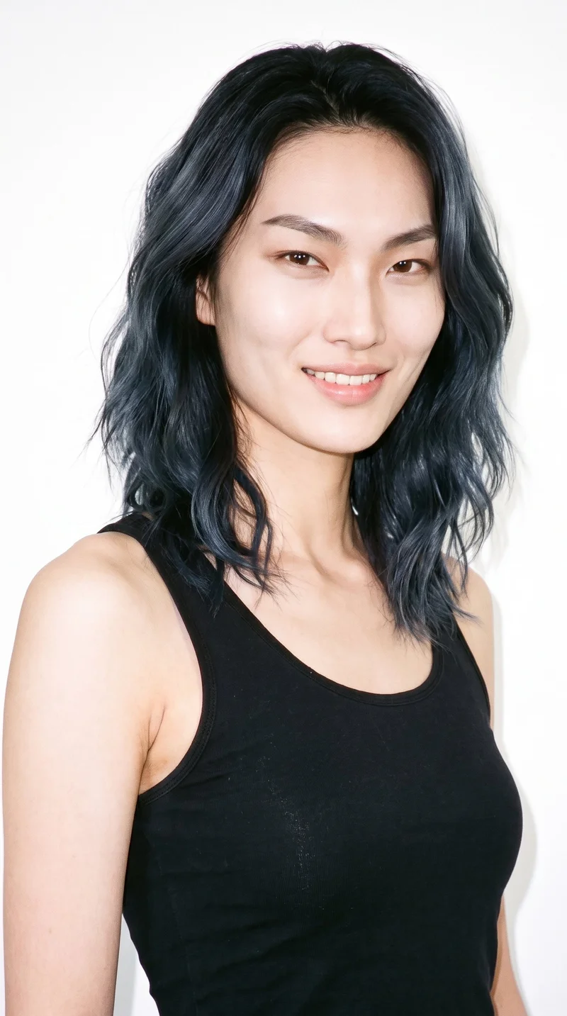A 30-year-old Korean woman with fair skin and a cool undertone. Her face has an angular structure with sharp, defined cheekbones and jawline. She has thin eyebrows, brown eyes, and thin lips. Her black hair is styled in loose, slightly tousled beach waves with natural volume. No facial hair is recorded.