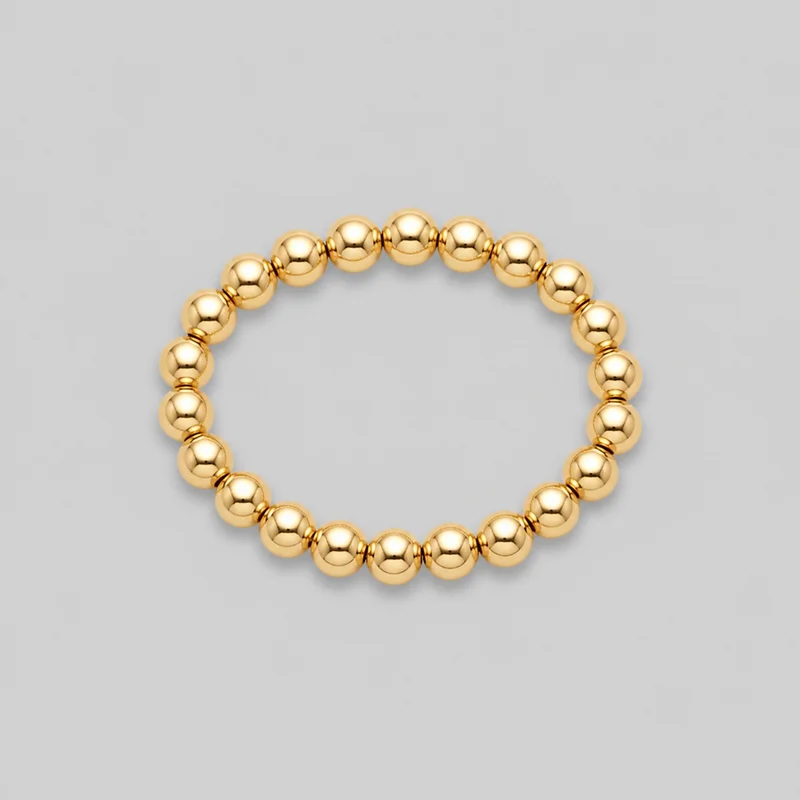 A complete circular women's gold-tone beaded bracelet is shown as a standalone product. It consists of smooth polished spherical beads with narrow ring-like spacer details between them, with no visible clasp, logo, print, engraving, or additional embellishment.