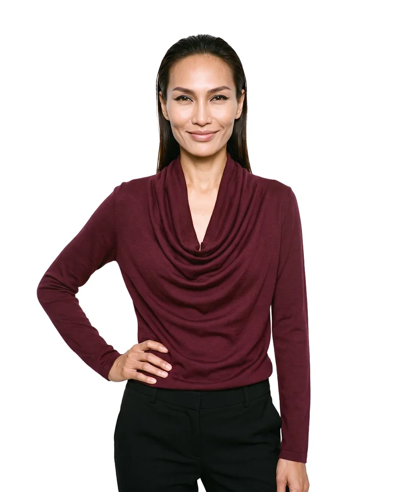 A 38-year-old Southeast Asian woman models a burgundy cowl-neck top in an upper-body, front-facing view. She stands with one hand on her hip and a natural expression against a pure white backdrop.