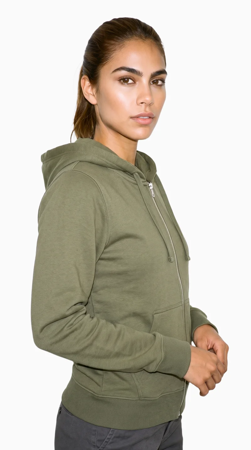 A 24-year-old Hispanic woman is shown from the upper body wearing a women's olive zip-up hoodie. She is posed with her hands in front in a front three-quarter view, against a flat Seasalt-colored backdrop.