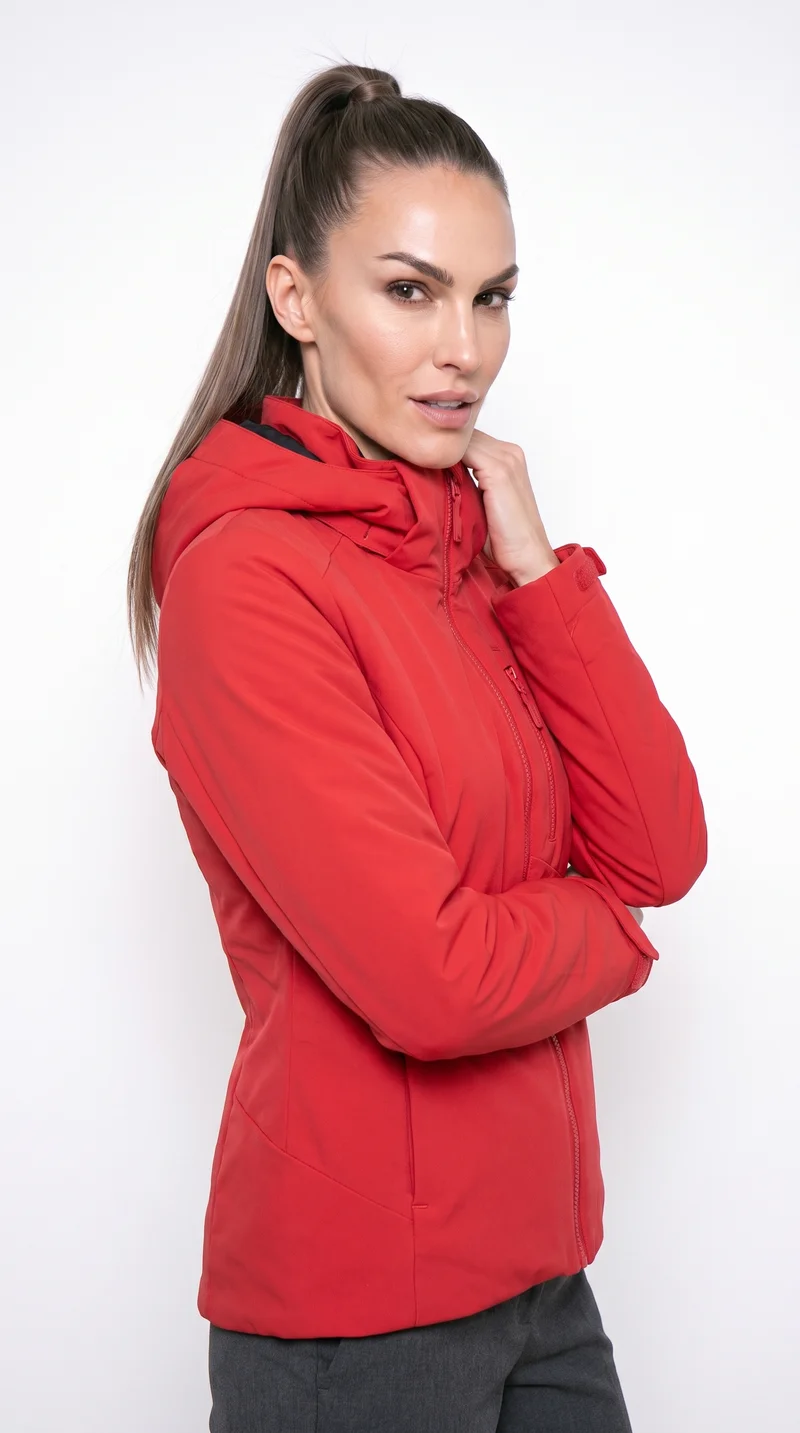 A 35-year-old Caucasian woman wears a red insulated ski jacket, shown from the upper body at a front three-quarter angle with one hand on her neck and a curious expression. A museum gallery serves as the backdrop.