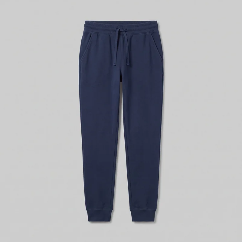 A complete front view of women's navy cotton jogger sweatpants. The joggers have an elasticated waistband with a center drawstring, two slanted front hip pockets, a visible center front rise seam, side seams, tapered leg panels, and fitted ribbed ankle cuffs.