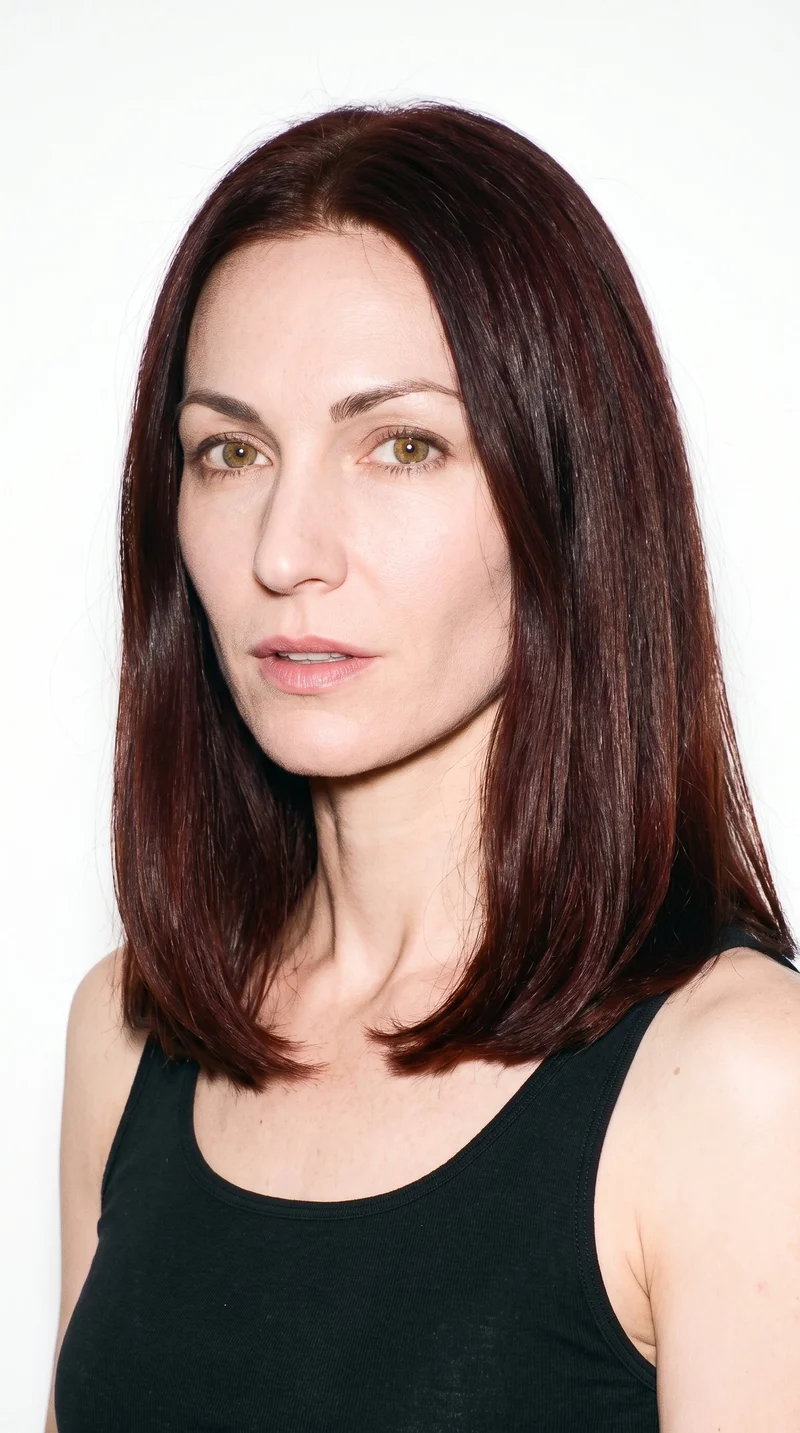 A 36-year-old Caucasian woman with medium skin and a peach undertone. Her oval face has balanced proportions and a softly rounded jaw. She has medium-thickness eyebrows, hazel eyes with green-gold flecks, and full lips. Her mahogany hair has a deep-brown base with a reddish-violet sheen and is styled in a long bob falling between the chin and shoulders.