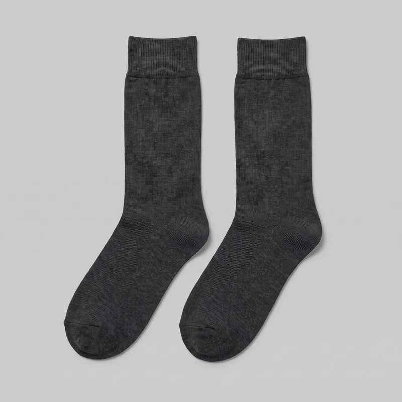 A complete pair of charcoal crew socks is laid flat, showing the wide ribbed cuffs, straight tubular shafts, smooth fine vertical knit texture, shaped heels, rounded toes, and visible toe seams. No logos, prints, patches, embroidery, or embellishments are visible.