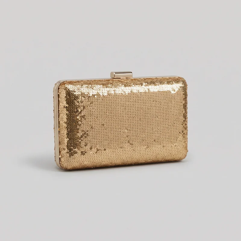 A structured rectangular gold sequin clutch is shown alone in a three-quarter view. The hard-sided bag has rounded corners, a flat front panel, a narrow side gusset, a rigid frame along the top and sides, and a centered rectangular push-lock clasp on the top edge. No handle or shoulder strap is visible.