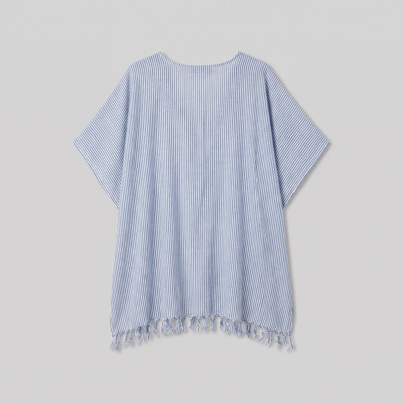 A standalone view shows a relaxed poncho-style beach cover-up with a loose rectangular body, wide shallow boat neckline, dropped shoulders, and broad short sleeves. Narrow vertical stripes run through the garment, ending in individual knotted fringe tassels along the straight lower hem.