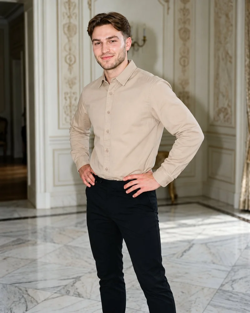 A 24-year-old Caucasian man wears a beige twill overshirt in a three-quarter-length, angled front view. He is smiling with his hands on his hips, against a mansion foyer backdrop.