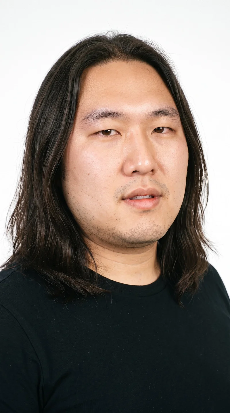 A 37-year-old Chinese man with East Asian facial features and lightly tanned, fair skin with a warm yellow undertone. His square face has a broad forehead and a strong, defined jaw, creating an angular, structured appearance. He has medium-thickness eyebrows, brown eyes, and medium-sized lips. His dark-brown hair is long, worn loose past the shoulders with natural volume. He is clean-shaven, with smooth skin across the entire face.