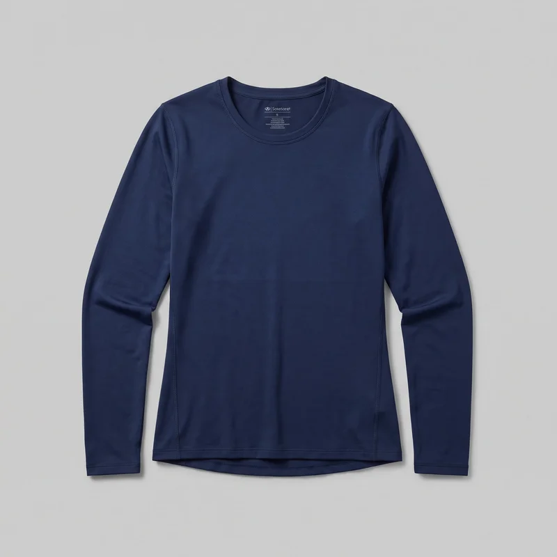 A women's navy slim-fit long-sleeve crewneck base layer top is laid flat in a mostly complete front view. The top has raglan-style sleeves, a bound crew neckline, visible flatlock-style seam detailing, and a slightly curved drop-tail hem layered beneath the front hem.