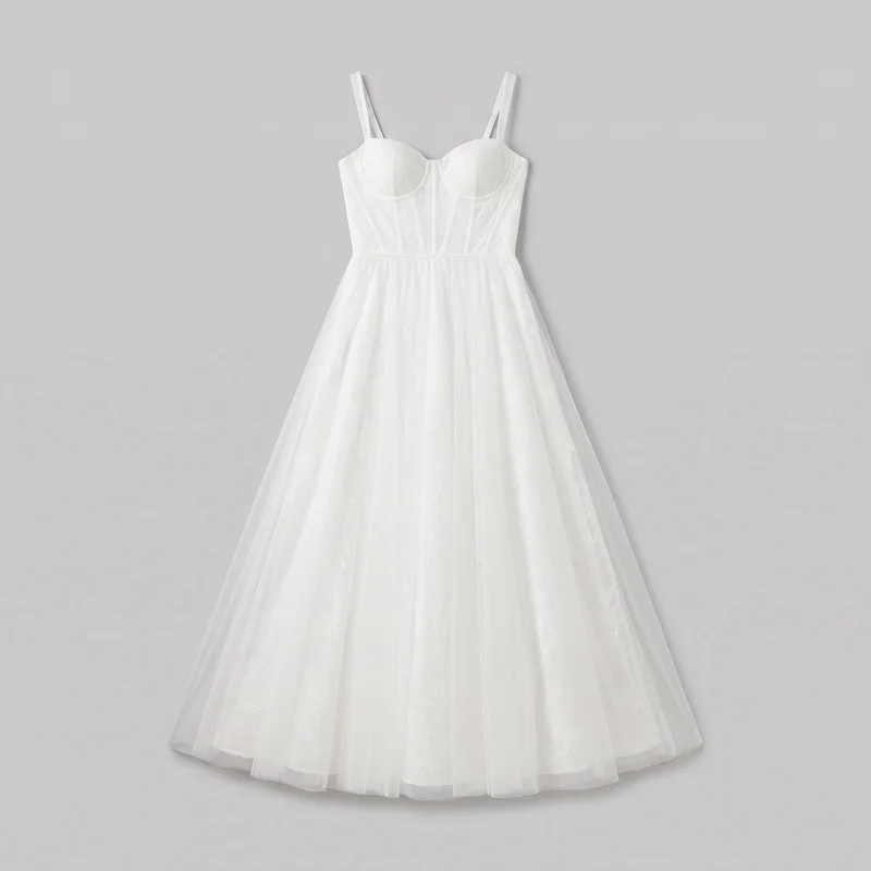 White formal bridal-style A-line gown shown in a complete front view against a plain backdrop. The dress has a structured bustier bodice with separate sweetheart cups, double shoulder straps on each side, curved under-bust seams, visible vertical boning channels, and panel seams leading to a defined waist. Its full floor-length skirt flares broadly from the waist with soft gathers or pleats and a slightly rounded hem, with subtle floral embroidery or lace-like motifs across the bodice and skirt.