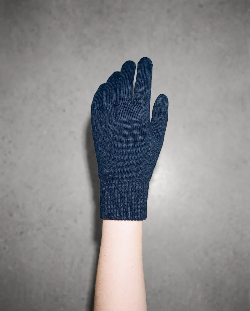 Women's navy touchscreen gloves shown on a hand and wrist from a top view, with the hand angled. A Chantilly Lace studio-wall backdrop is visible.