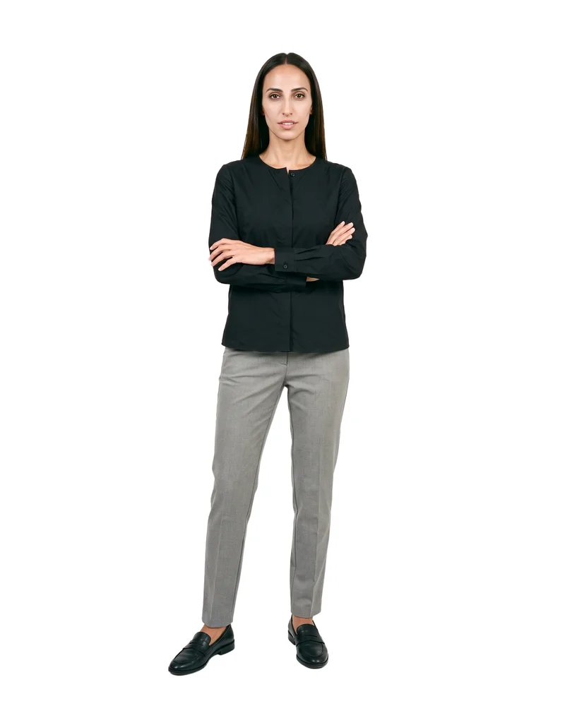 A 33-year-old Arab woman wears a black classic blouse in a front-facing environmental composition, with her arms held low and a natural facial expression. A pure white backdrop surrounds the subject.