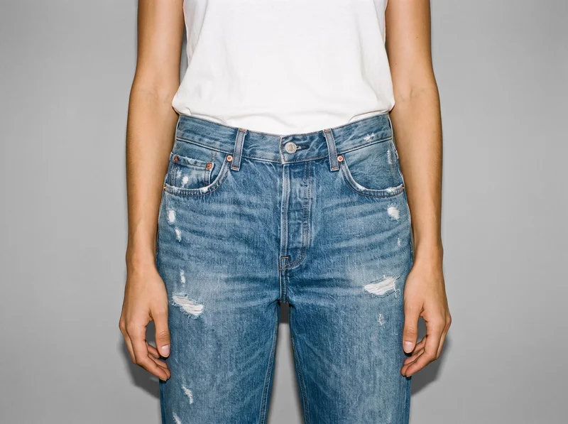 Women's distressed boyfriend jeans shown from the front, framed from the hips with the hips level. The jeans are presented against a Silver Mist studio-wall backdrop.