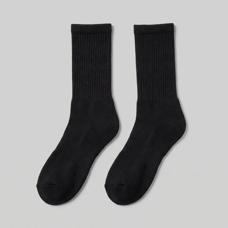A pair of black crew socks is laid flat with the full shafts, shaped heels, and rounded closed toes visible. The socks have vertical ribbed texture along the legs and insteps, defined top cuff bands, and visible toe seams.