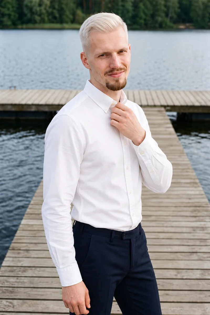 A 25-year-old Caucasian man wears a white Oxford shirt in an upper-body, angled-front view. One hand rests at his collarbone, and the background is a lakeside dock.