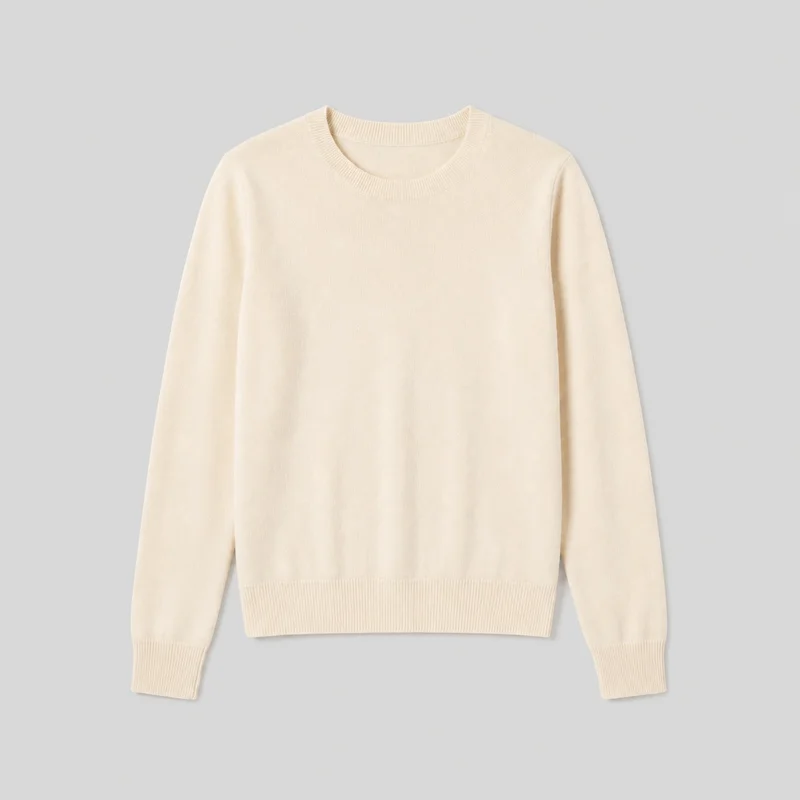 A mostly complete front view of a cream cashmere knit crewneck pullover sweater, laid flat or presented as a standalone product. It has a regular-to-relaxed straight silhouette, standard-length body, long sleeves with ribbed cuffs, and a rounded ribbed neckline and straight ribbed bottom hem.