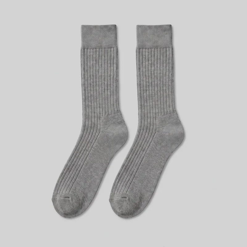 A pair of grey crew-length knit socks is laid flat, showing the full ribbed legs, wider folded-looking cuffs, shaped heels, foot sections, and rounded closed toes. Vertical ribbing runs through the legs and insteps, while the heel and toe areas have smoother knit shaping with visible toe seam lines. No logos, prints, patches, embroidery, or embellishments are visible.