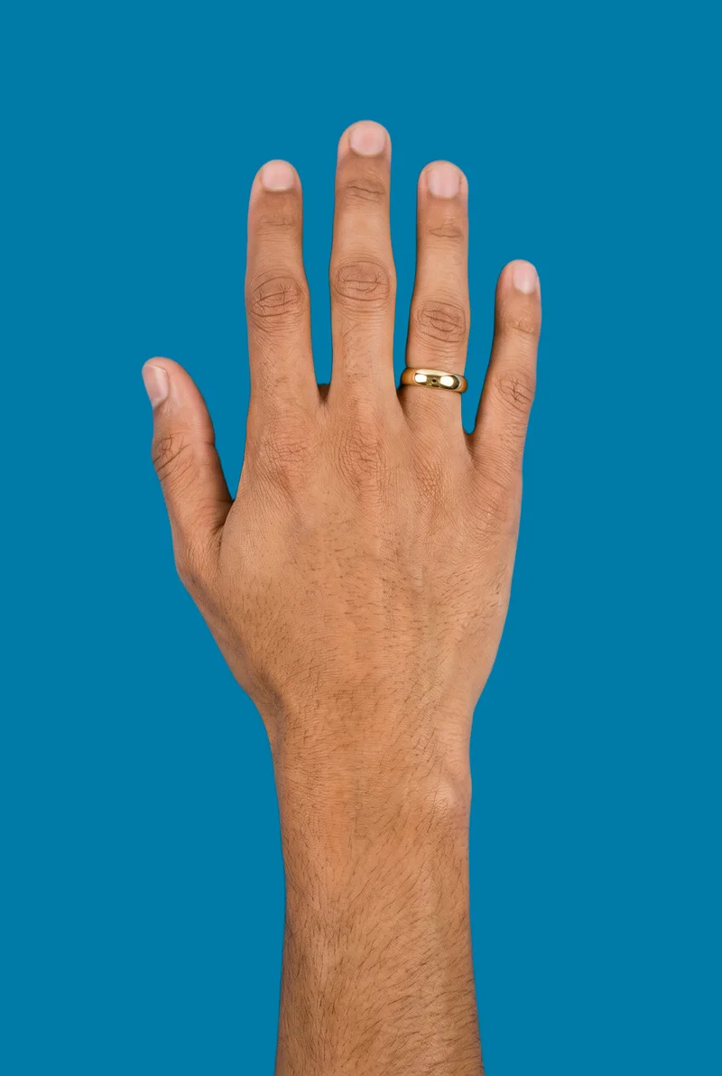 A man's hand and wrist are shown from above at an angle, wearing a gold band ring. The hand and wrist area is framed against a flat cerulean backdrop.