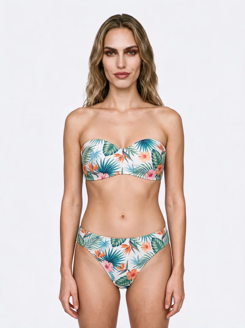A 19-year-old Caucasian woman is shown from the upper body in a front view, wearing a tropical print bikini. Her arms are relaxed and her expression is confident, against a flat porcelain-colored backdrop.