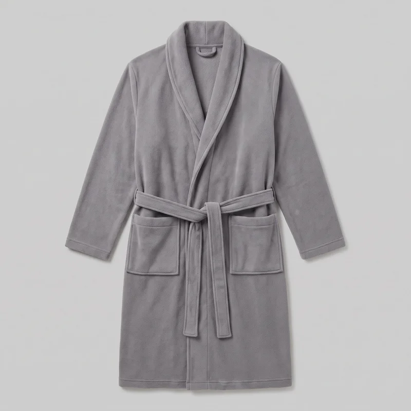 A mostly complete front view of a men’s grey fleece bathrobe with a relaxed straight silhouette, broad shawl collar, wrap front, and open V neckline. The long straight sleeves have simple cuff hems, while a self-tie waist belt is threaded through side loops and tied at the front with hanging ends. Two rectangular lower front patch pockets, raised binding along the collar, front opening, belt, pocket edges, cuffs, and straight hem are visible.