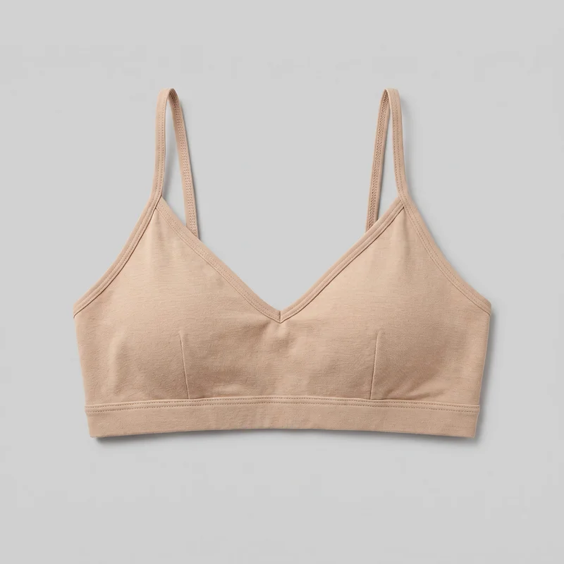 Beige women's bralette shown as a standalone front view. It has a close, body-skimming cropped fit, a deep V neckline, triangular soft cup shaping, narrow fixed shoulder straps, bound edges, an underbust band with multiple rows of topstitching, and vertical seams below the cups.