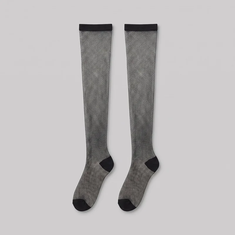 A complete matching pair of black thigh-high fishnet stockings is laid flat. Each stocking has an all-over diamond mesh pattern, a straight opaque top band, shaped foot with a defined ankle curve, and opaque reinforced toe cap and heel patch.