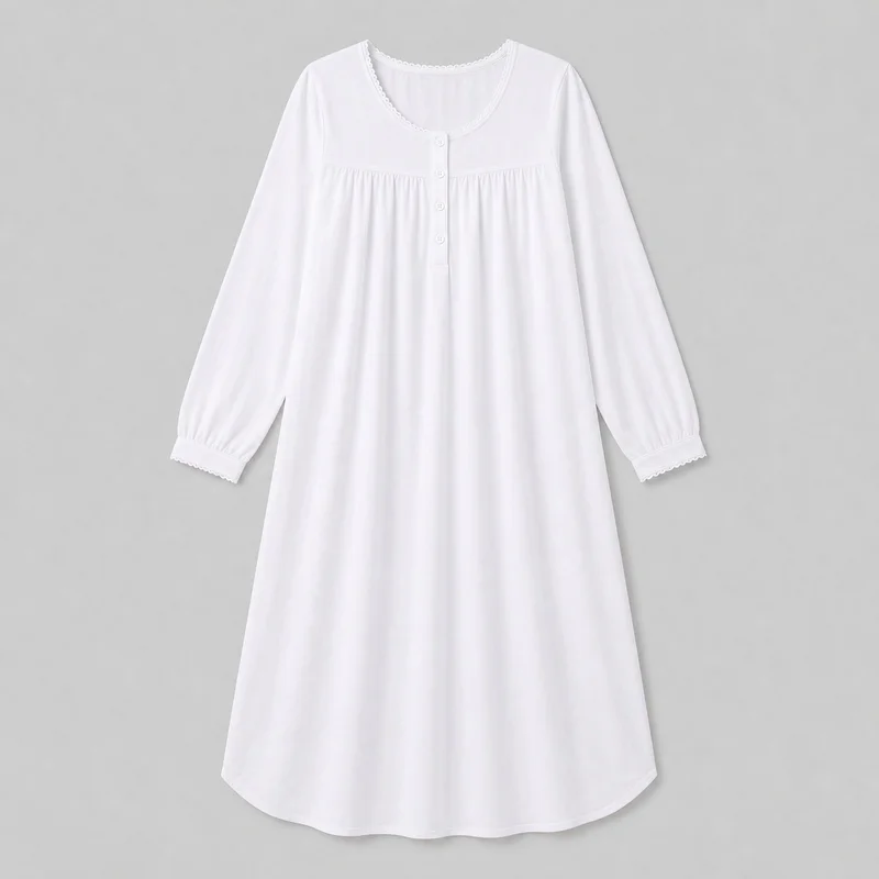 White cotton nightgown shown in a complete front view. The long sleep dress has an A-line silhouette, a rounded scoop neckline, a short centered button placket, a horizontal upper-chest yoke seam with gathered fabric below, long set-in sleeves with gathered cuff bands, narrow scalloped trim at the neckline and cuffs, and a softly curved full-length hem.
