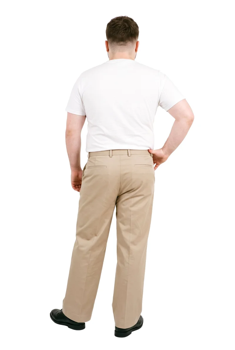 A 20-year-old Caucasian man is shown full body from the rear, wearing beige wide-leg tailored trousers with one hand on his hip. The trousers are presented against a pure white backdrop.