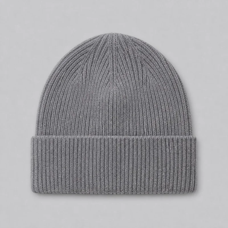 A complete grey knit beanie is shown laid flat from the front. It has a rounded crown, a broad folded lower cuff, and vertical rib texture continuing across both the crown and cuff.