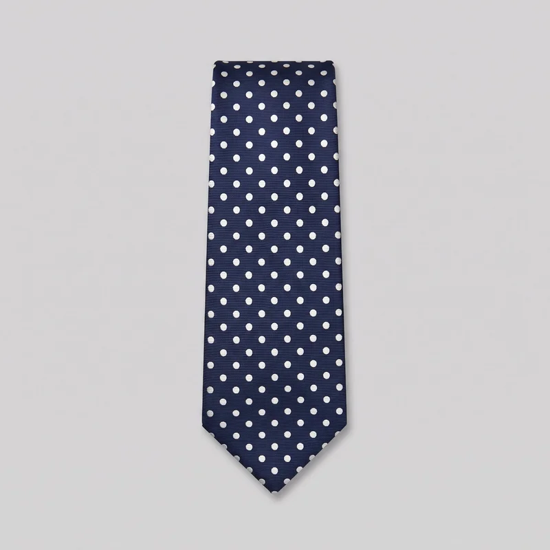 A classic necktie is shown flat as a standalone product, with a straight tapered blade, squared upper end, and pointed triangular lower tip. The tie has a fine horizontal woven rib texture and an evenly spaced all-over round polka-dot pattern, with no visible logos, labels, embroidery, or additional embellishments.