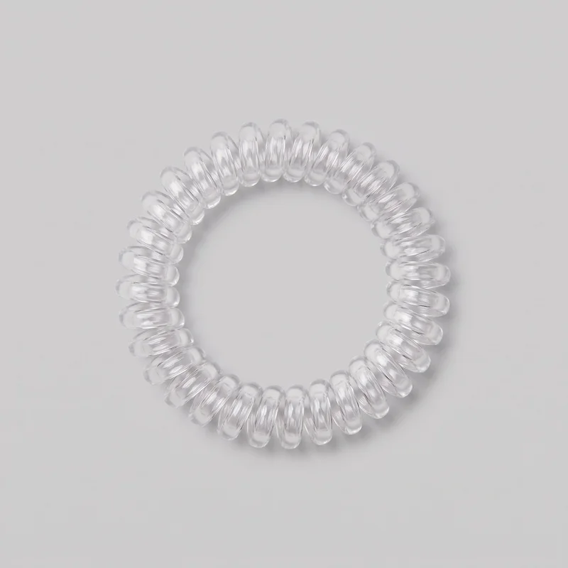 A complete spiral hair tie is shown alone from above. It forms a continuous telephone-cord-style ring with a hollow center and repeated rounded loops around the full circumference, creating smooth raised coil ridges with consistent spacing. No clasp, closure, logo, print, or embellishment is visible.