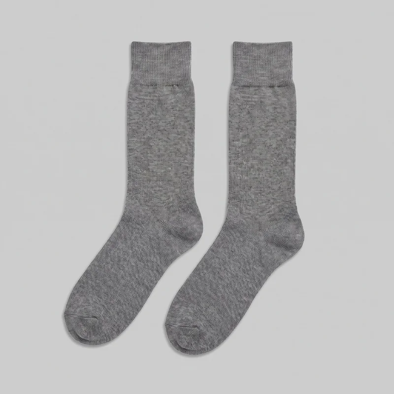 A pair of grey wool crew-length dress socks is laid flat, showing the full ribbed cuffs, straight sock legs, shaped heel pockets, foot sections, rounded closed toes, and visible toe seams. The socks have a plain knit design with no logos, prints, closures, pockets, patches, embroidery, or other embellishments.