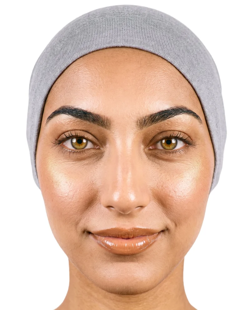 A 19-year-old Arab woman wears a grey underscarf, shown in a head-framed front view with her head level and a natural expression. The item is presented against a pure white backdrop.