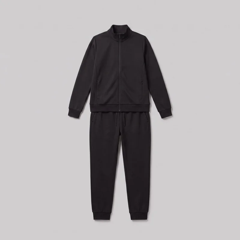A standalone front view of a black two-piece tracksuit set, featuring a regular-fit zip-front jacket with a high stand collar, long sleeves, ribbed cuffs, vertical lower-front zip pockets, and a ribbed straight hem. Matching jogger pants have a visible drawstring waistband, tapered full-length legs, side pockets, and ribbed ankle cuffs. No logos, prints, patches, embroidery, or embellishments are visible.