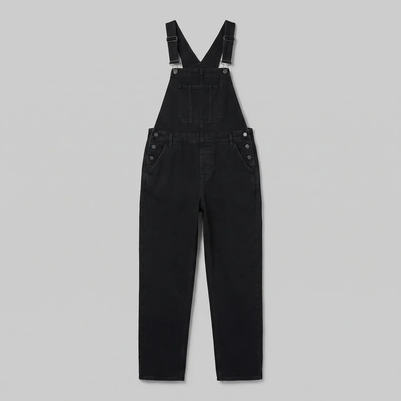 Black denim bib overalls laid flat in a full front view. The overalls have wide adjustable shoulder straps with slider buckles, a high bib front with a divided patch pocket, an open side waist construction, a horizontal waistband with belt loops and button tabs, curved front hip pockets, a visible fly seam, contrast topstitching, and straight full-length pant legs with plain hems.